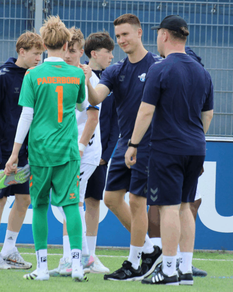Ein Fußballtrainer des SC Paderborn 07 klatscht einen Spieler ab.